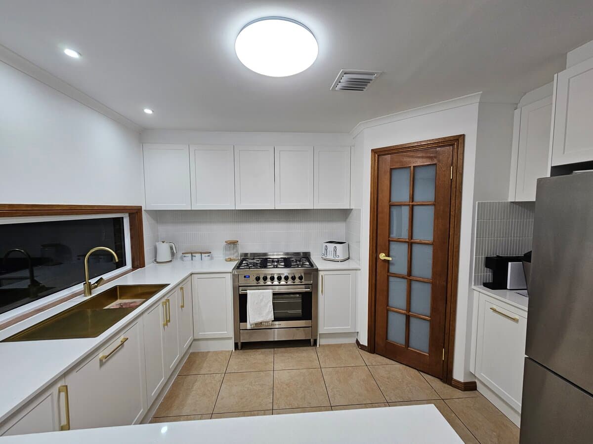 Modern white kitchen with gold fixtures after ELLA renovation